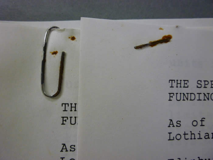 A rusted paper clip and staple on two sheets of paper