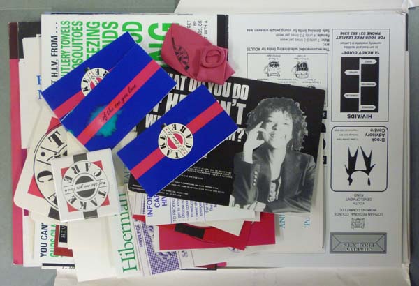 A sample of objects taken from an HIV/AIDs collection, consisting of modern paper materials, balloons, condoms and badges